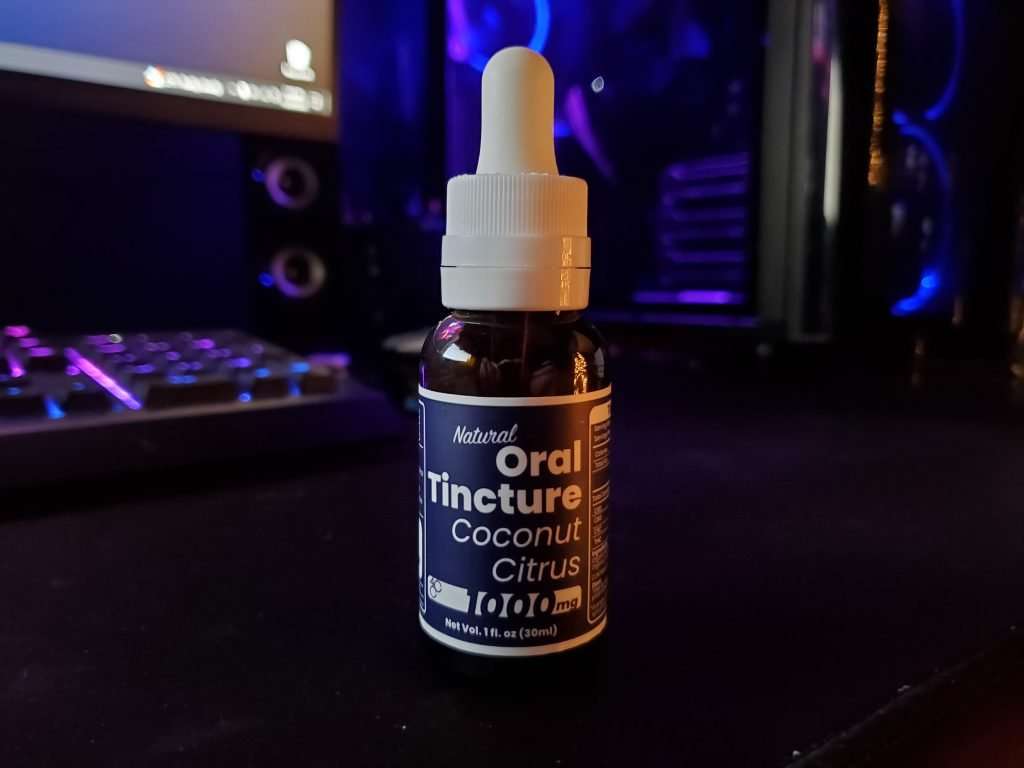 30 ml bottle of 4 Corners Cannabis CBD tincture with blue and purple computer and keyboard in background