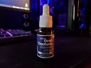 30 ml bottle of 4 Corners Cannabis CBD tincture with blue and purple computer and keyboard in background