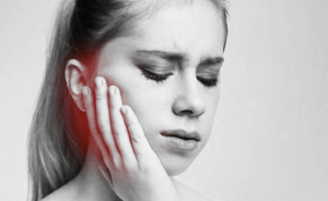 Black and white photo of a woman holding her jaw in pain
