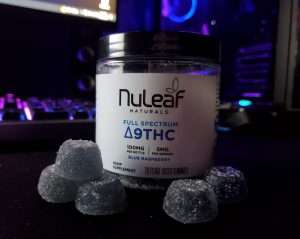 NuLeaf Naturals Delta 9 THC Gummies Review. Image includes a bottle of NuLeaf Naturals Delta 9 THC gummies with five blue gummies in front.